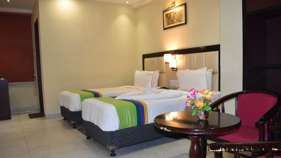 a view of the deluxe room furnished with plush beds chairs and table placed by its side - Click Hotel Capital House, Patna