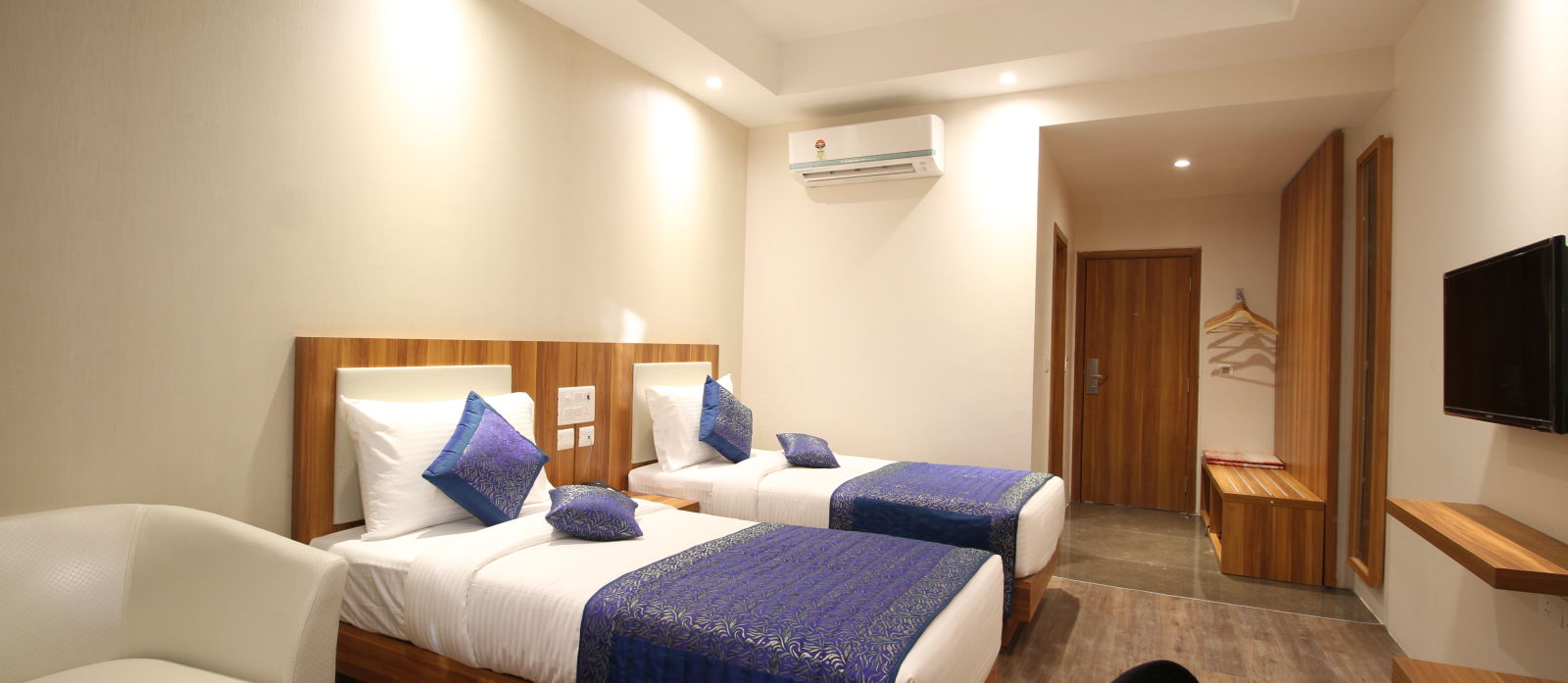 deluxe room with twin beds captured from different angles that showcase the in-room amenities and interior of the bedroom - le roi raipur hotel1