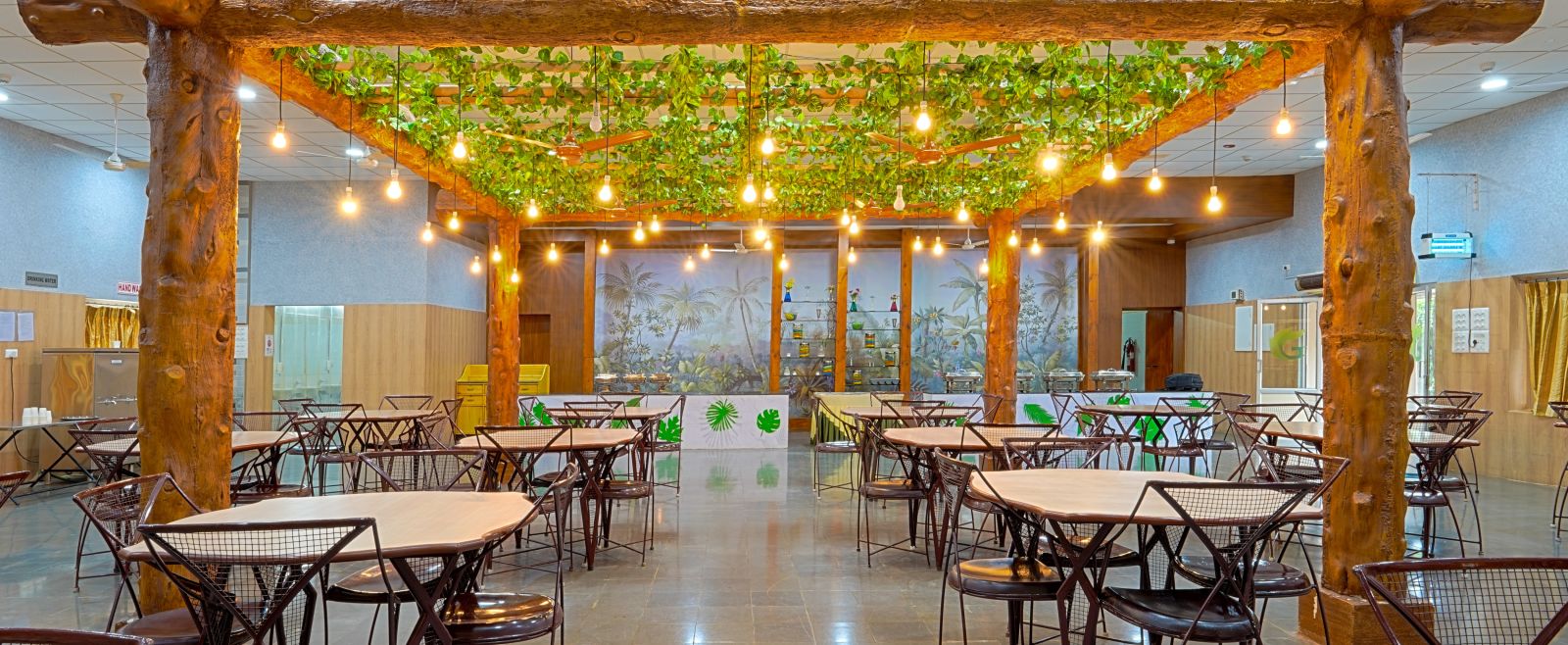 well-lit restaurant with tables and chairs with light bulbs hanging from the ceiling at Greens Inn