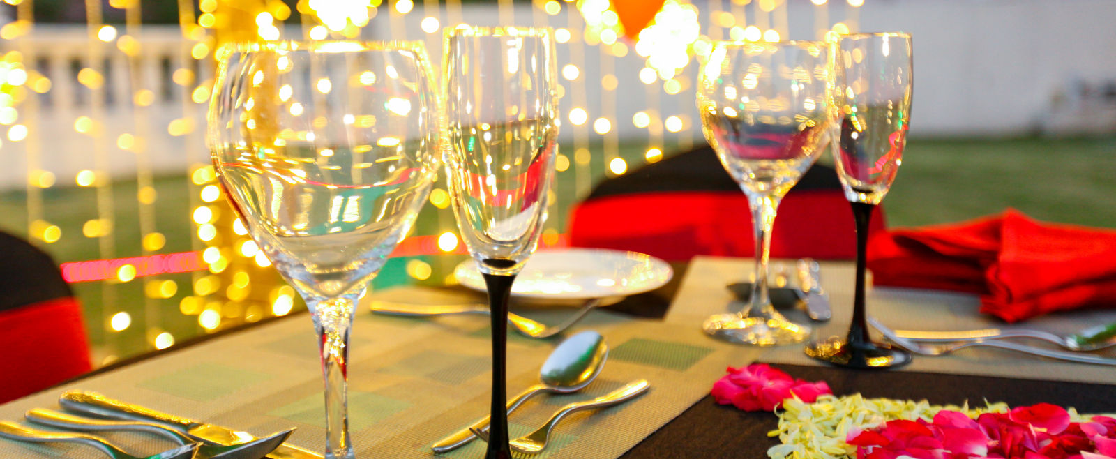 glasses set on a table with plates, cutlery and decoratations in the backdrop 