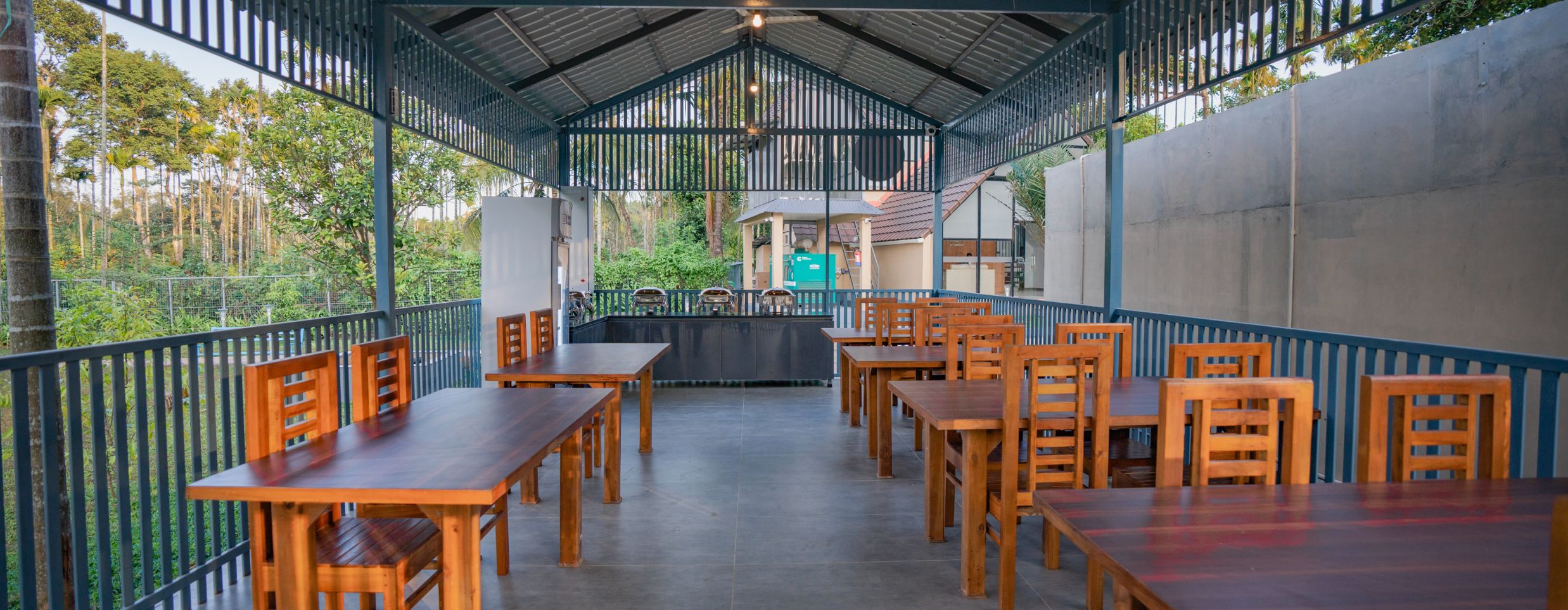 Dining area with wooden tables and trees at Feel Free Retreat, Wayanad