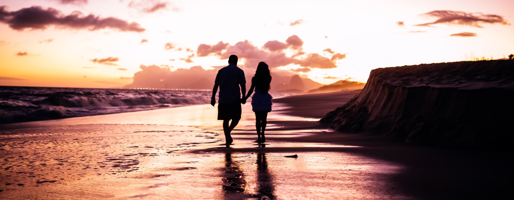 valentine day special in mumbai - a couple holding hands and walking on a sea beaching during sunset