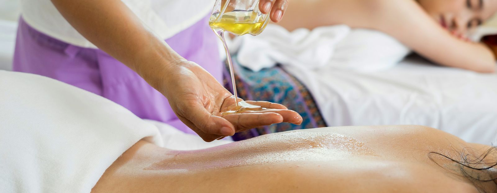 A person receiving a traditional oil massage from a masseuse