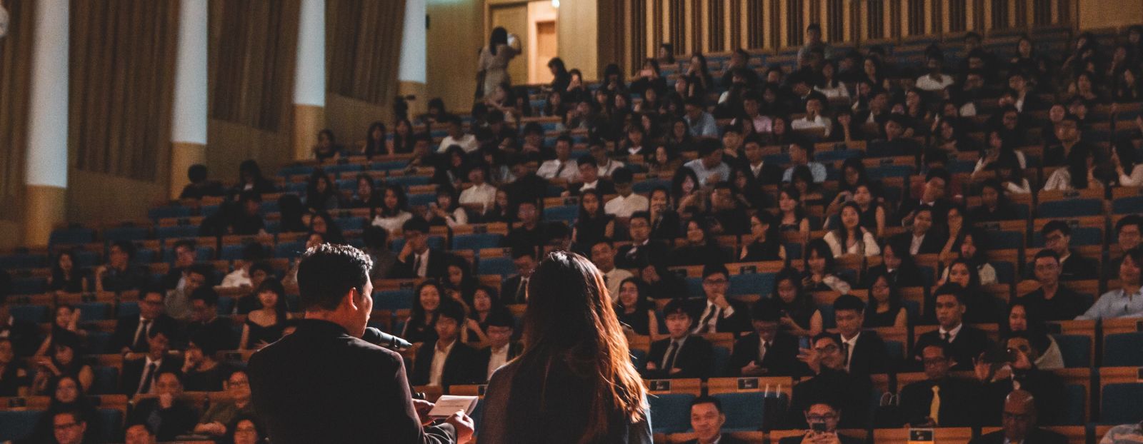 Speakers addressing a large audience at a conference