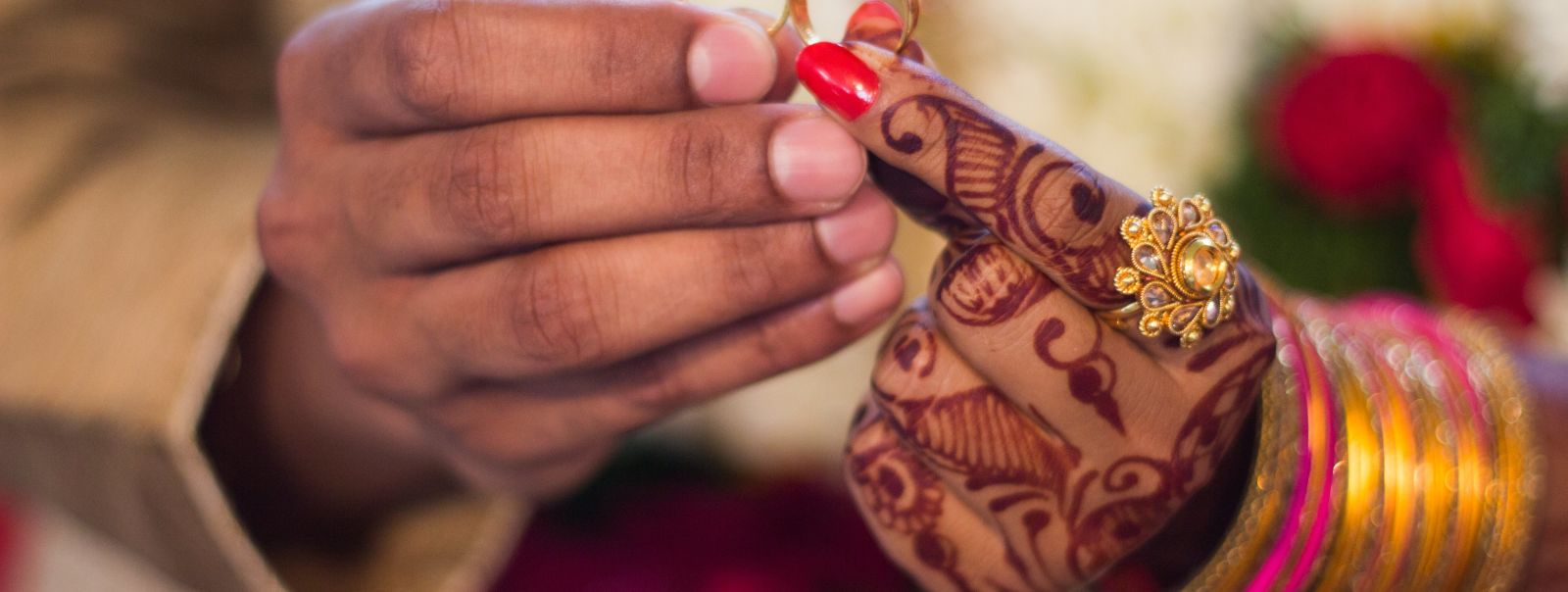 A close-up of a people's hands exchanging wedding rings