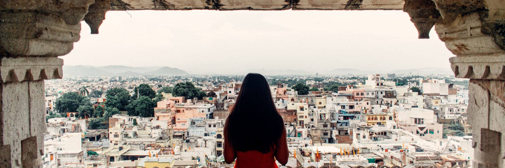 A girl looking out of a balcony of an old palace of the amazing view of the city of Udaipur