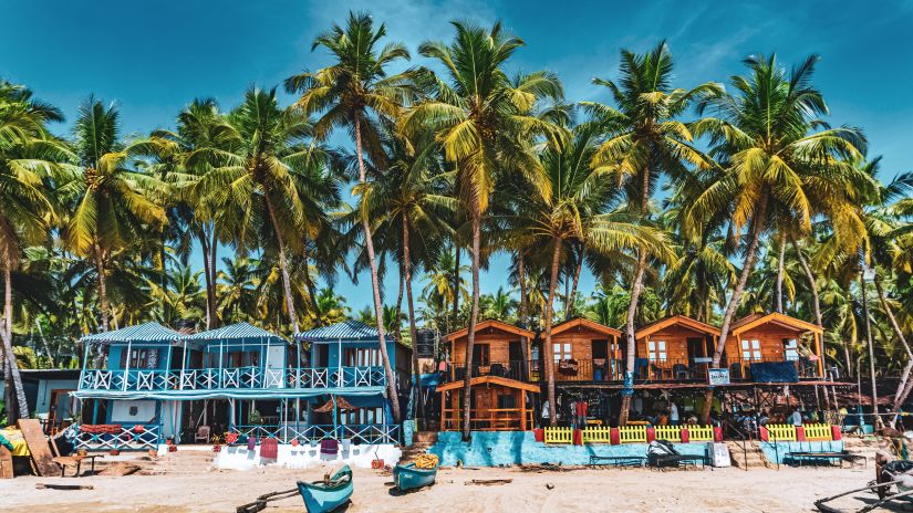 The palm trees and blue and brown shacks on Palolem Beach