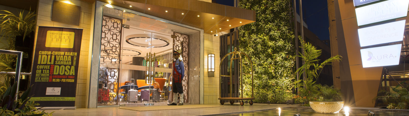 The exterior entrance of a hotel at dusk, featuring signage, a bellhop and a reflective water feature - Hotel Southend By TGI - Bommasandra, Bangalore