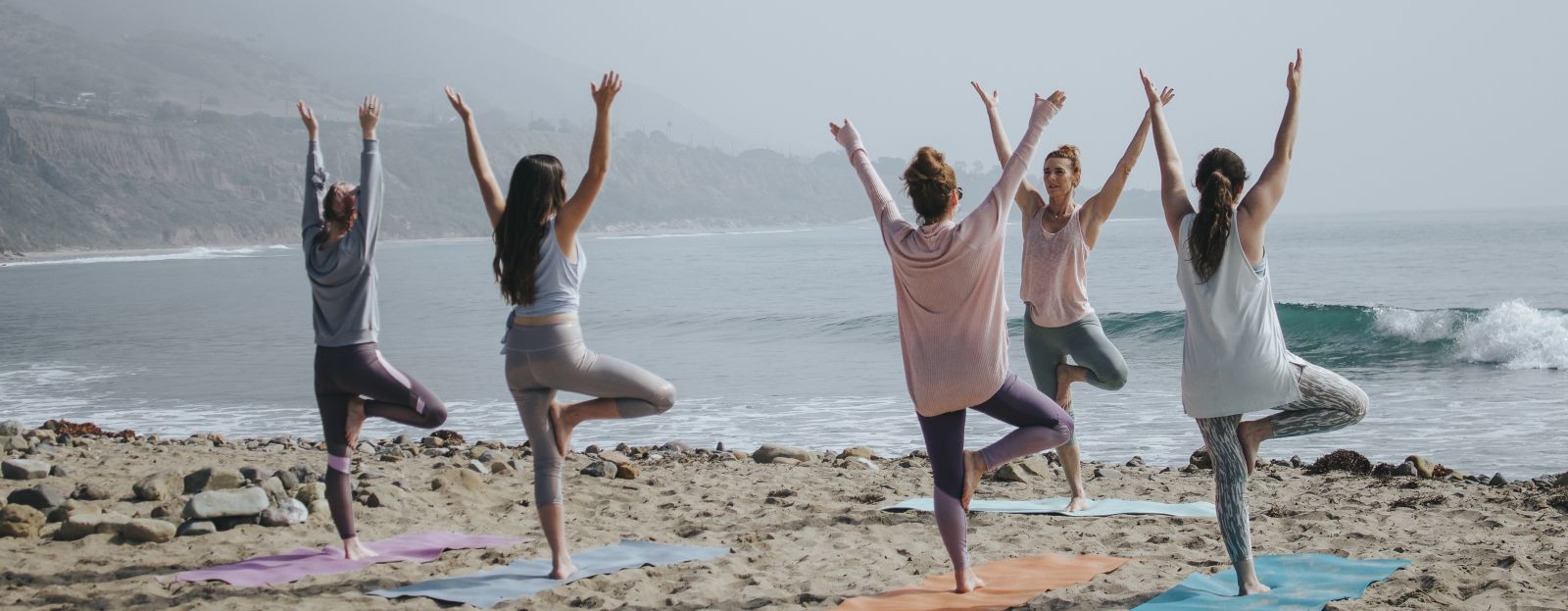 People doing group yoga at beach looking in to the horizon