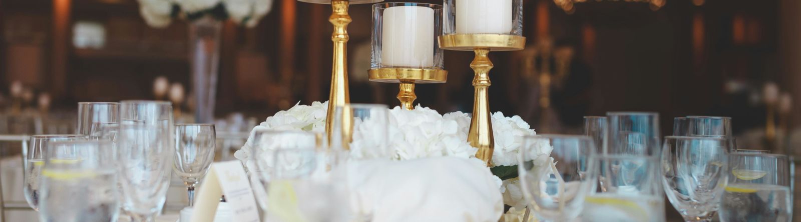 Sophisticated banquet table with gold candlesticks and white floral centrepieces