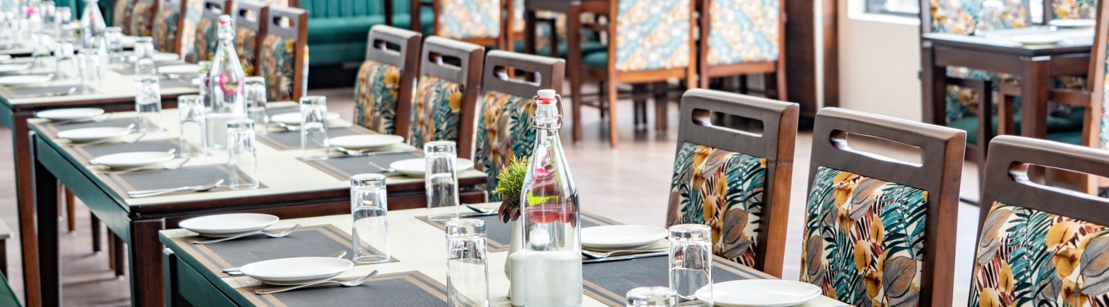 A close up shot of a long table with plates and cutlery in our restaurant - Shervani Pebbles & Pines, Corbett