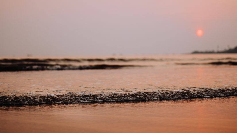 a beach with the sun in the background