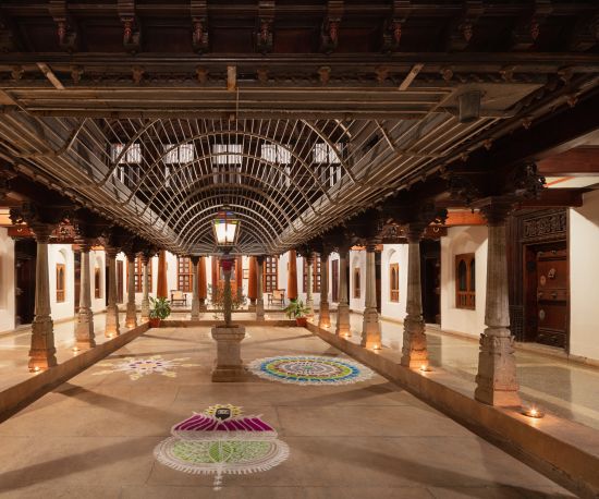 alt-text Interior of Chidambara Vilas Resort showing a spacious, traditional Indian assembly hall with ornate wooden architecture and stained glass