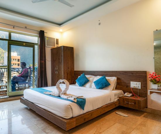 alt-text A double bed in the premium room at Vinsober Pride Inn, Rishikesh