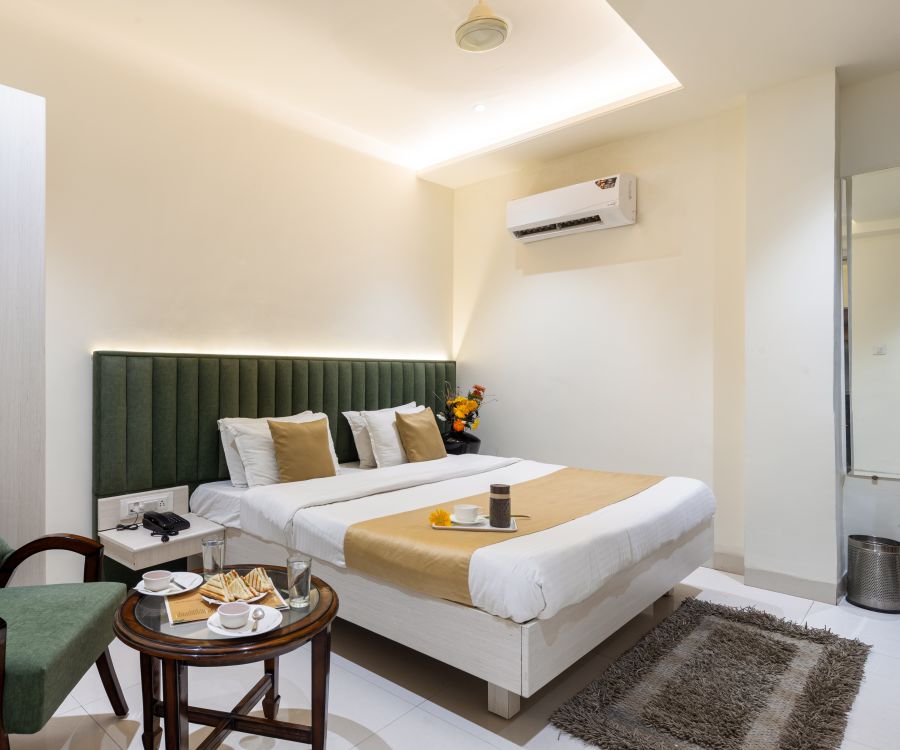 alt-text A room featuring a green sofa chair, a coffee table, a/c, wardrobe and neat bed - Hotel Meghdoot, Bhopal