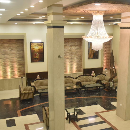 A high low shot of the lobby with sofa sets, coffee tables and a chandelier on the top | Hotel City Inn, Varanasi