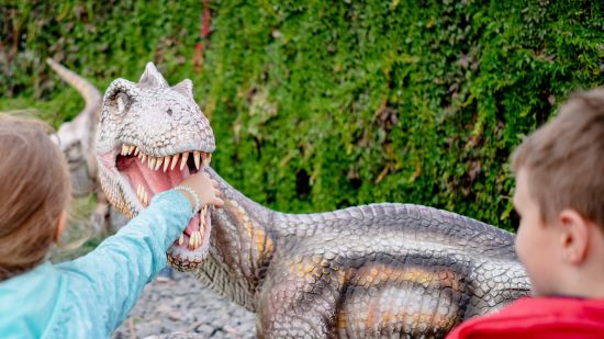 Children playing with a dinasaur statue