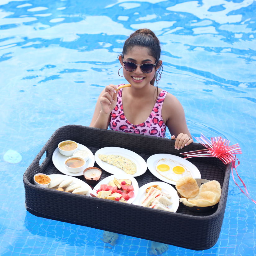 a woman posing in the swimming pool with a floating breakfast tray with many items inside - Shanti Seaview Resort & Spa