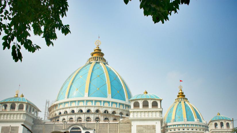 an image of the famous ISKCON temple captured with a monkey in front 