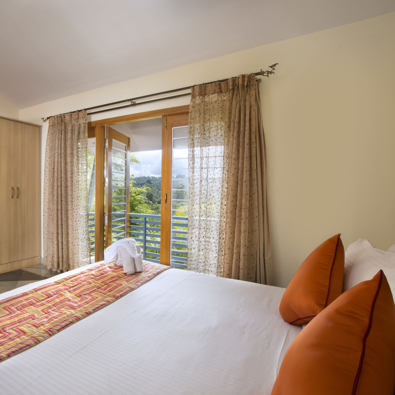 Captivating glimpses include a room adorned with a plush bed, inviting pillows, a television and a balcony offering panoramic mountain vistas - Kairos, Yelagiri