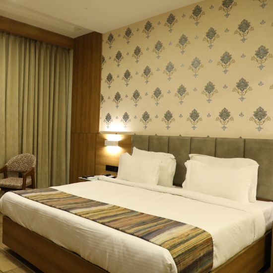 Executive Room at Comfort Resort, Morbi with plush bedding covered in white bed cover and grey duvet