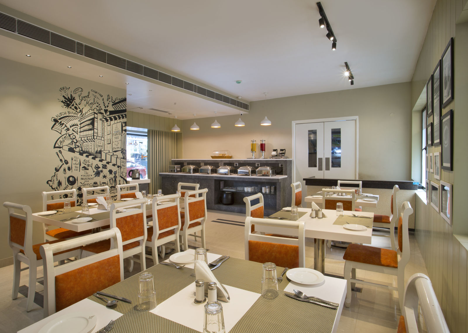 A modern and well-lit buffet restaurant interior with white chairs and orange cushions - Hotel Langford Keys by TGI, Shanti Nagar