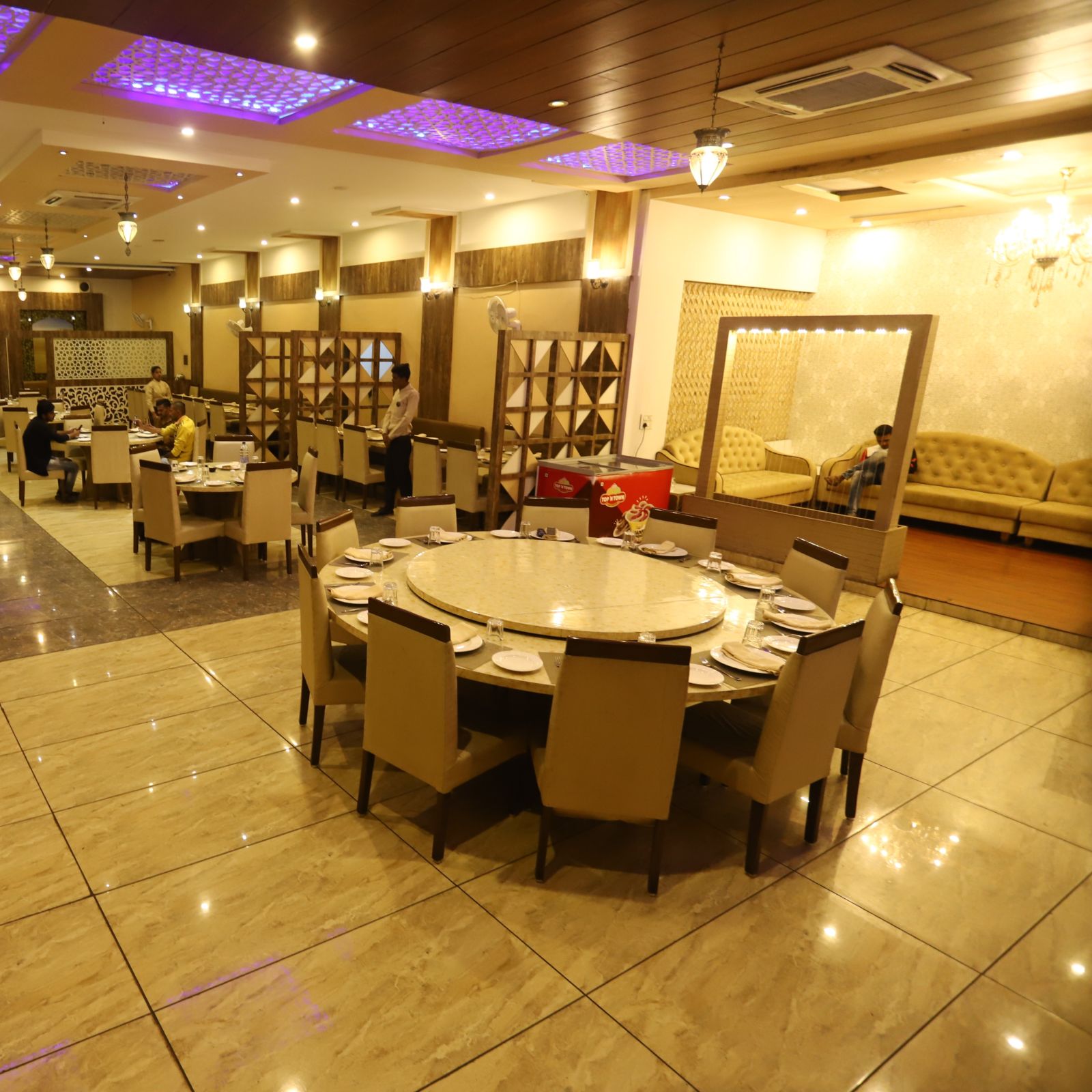 interior of Meadha restaurant at Hotel Manaal By M Square, Pithampur featuring round tables and chairs placed around it