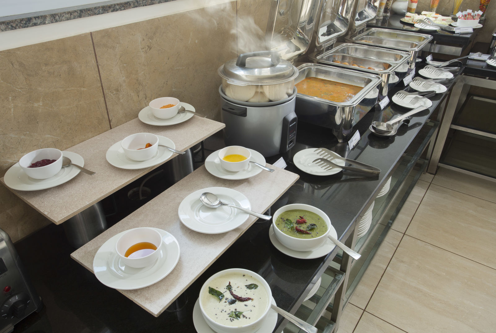 A buffet table with a selection of soups and hot dishes in a hotel dining area - De Venetian by TGI, Brookefield