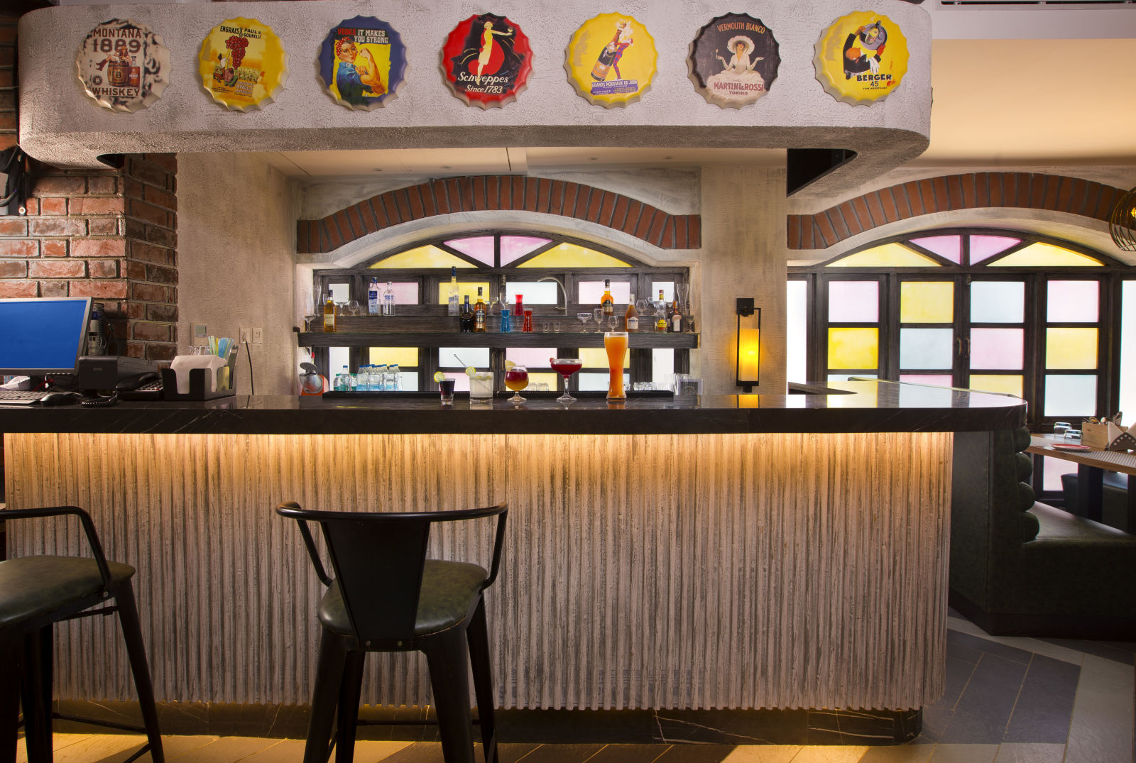 A stylish bar with colourful stained glass windows, a variety of drinks on display and vintage advertisements on the wall - Hotel Southend By TGI - Bommasandra, Bangalore