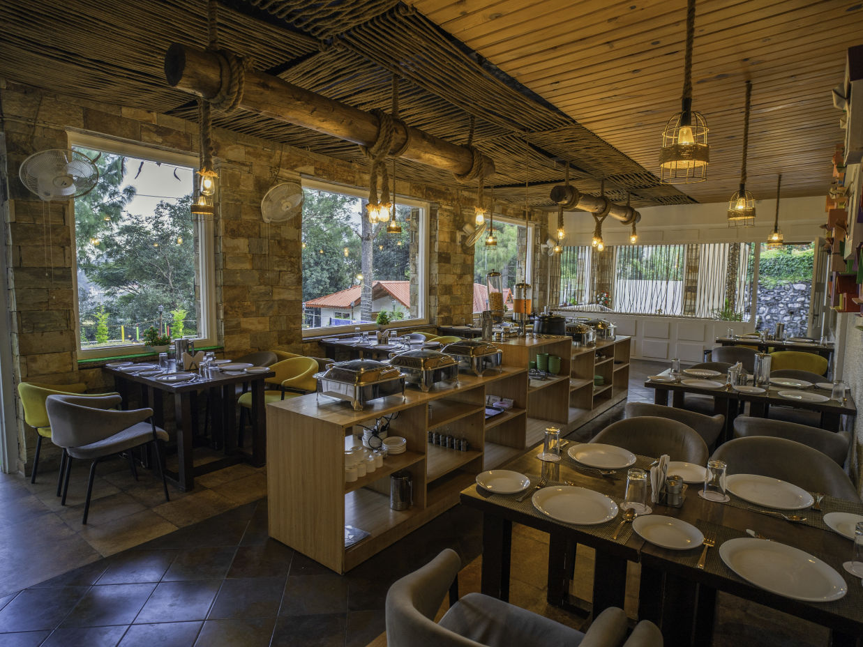 A restaurant featuring several tables and chairs - The Nature's Green Resort, Bhimtal