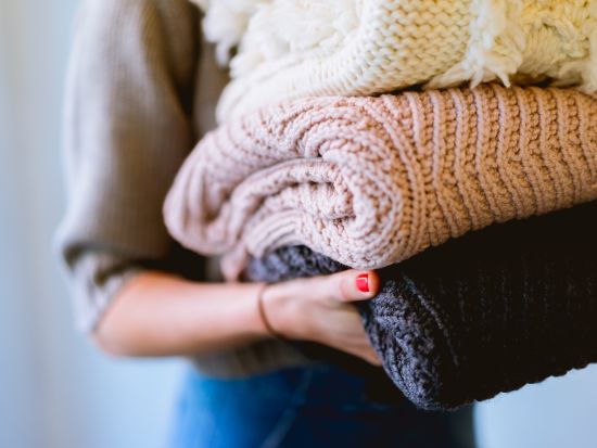 a woman with red nail paint holding many items of clothing