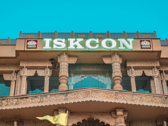 The facade of the ISKCON temple with intricate architecture and the name in large green letters.