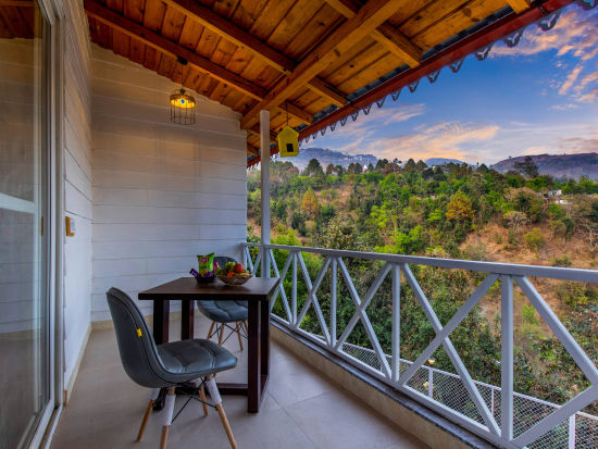 A balcony with two chairs and a table facing a scenic mountain view - The Nature's Green Resort, Bhimtal