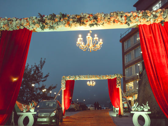 A decorated outside venue featuring red curtains held up by pillars - The Orchid Hotel Shimla