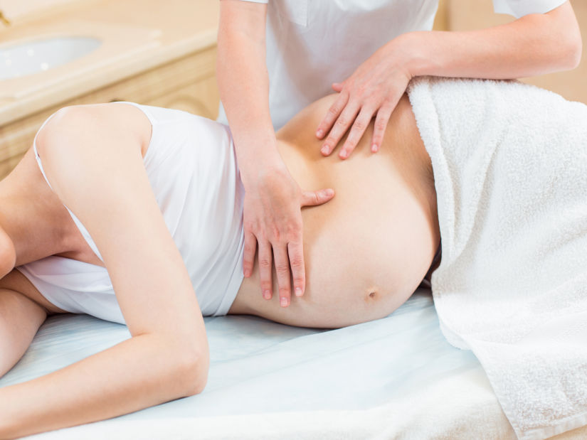 A pregnant lady getting a massage by a masseuse