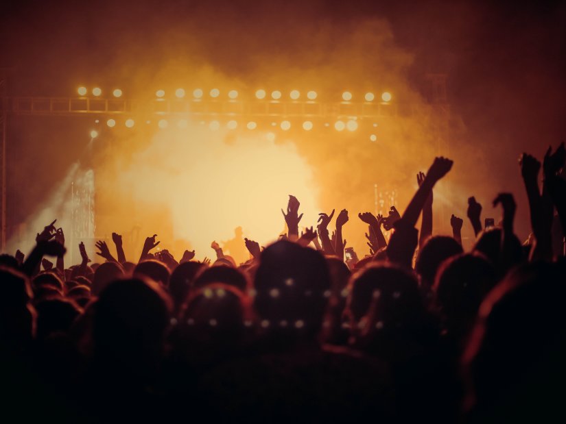 people with their hands raised in the air at a concert at night