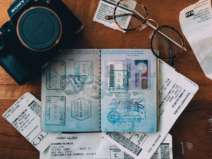 An open passport along with a camera glasses and other papers