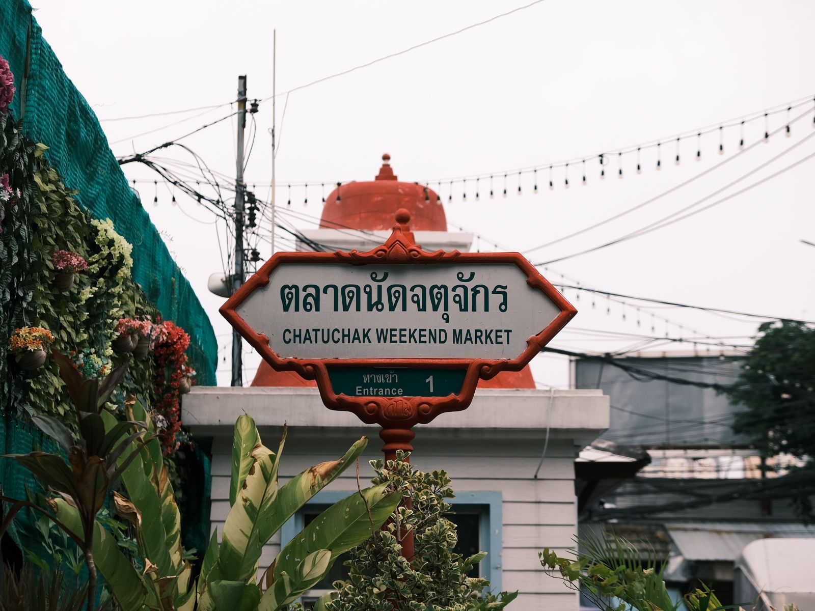 a signage of Chatuchak Weekend Market at the entrance of the event space with white clouds in the background