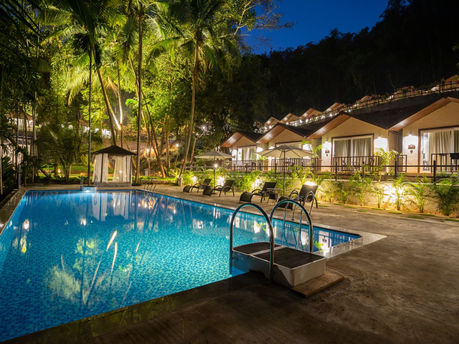 A night view of Stone Wood Nature Resort Gokarna with the pool and the cottages