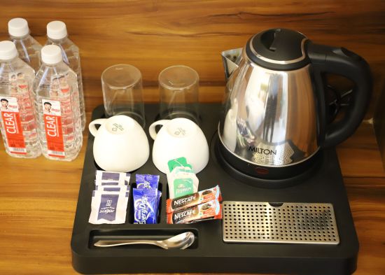 alt-text A picture consisting cups a kettle coffee and tea bags and packed water bottles - Opulent Inn by lime tree hotels