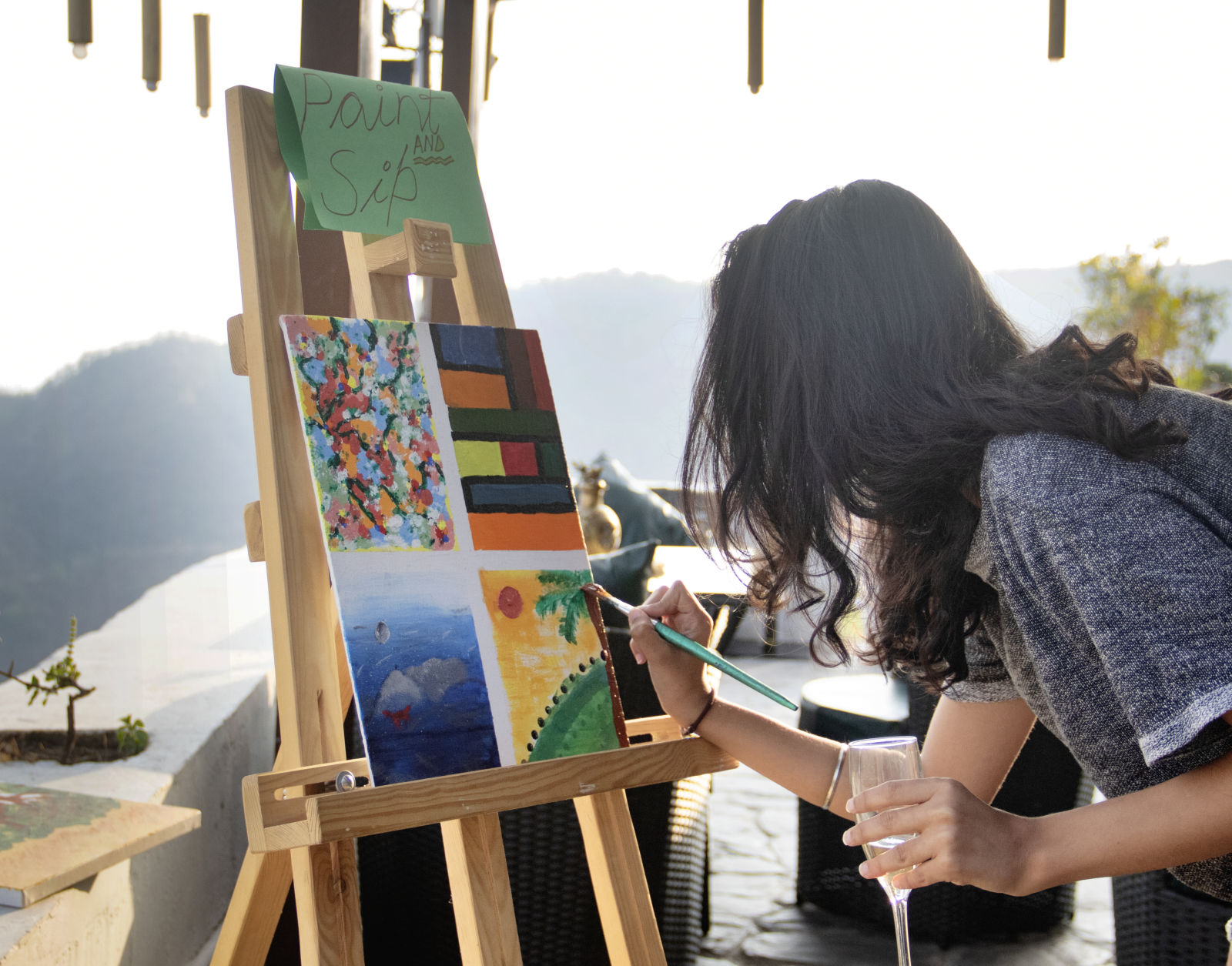 a girl paining on a canvas with mountains in the background