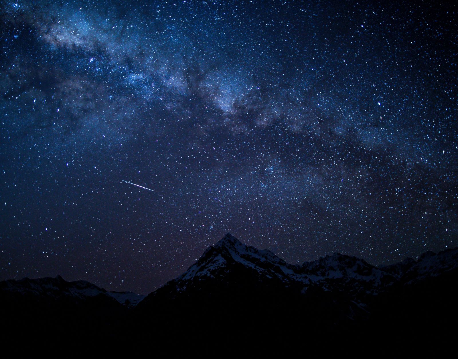 a star lit sky with mountains in the foreground