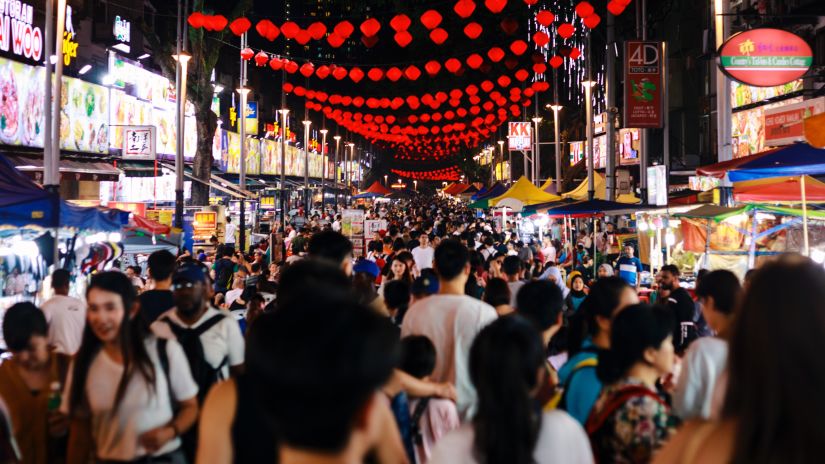 People walking through a market with stalls on both sides