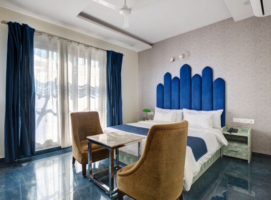 alt-text Blue themed Superior Deluxe Room with king size bed and chairs - The White Moon