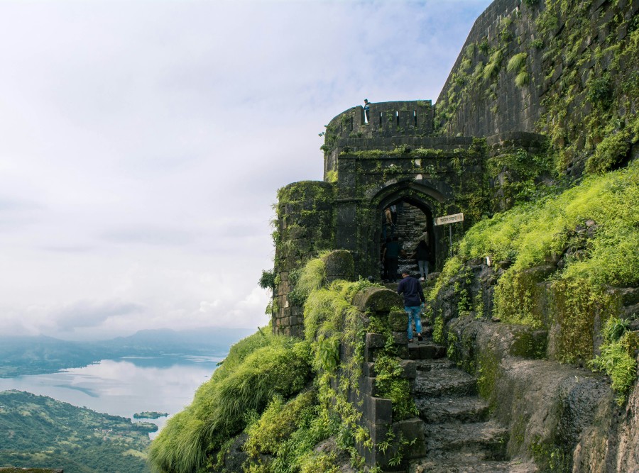 alt-text Ancient stone steps and archways covered with green moss on a foggy mountain, evoking a sense of mystery and historical depth in a natural setting.