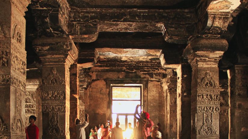 an image taken from inside a Temple with the entrance in the background and people walking from it