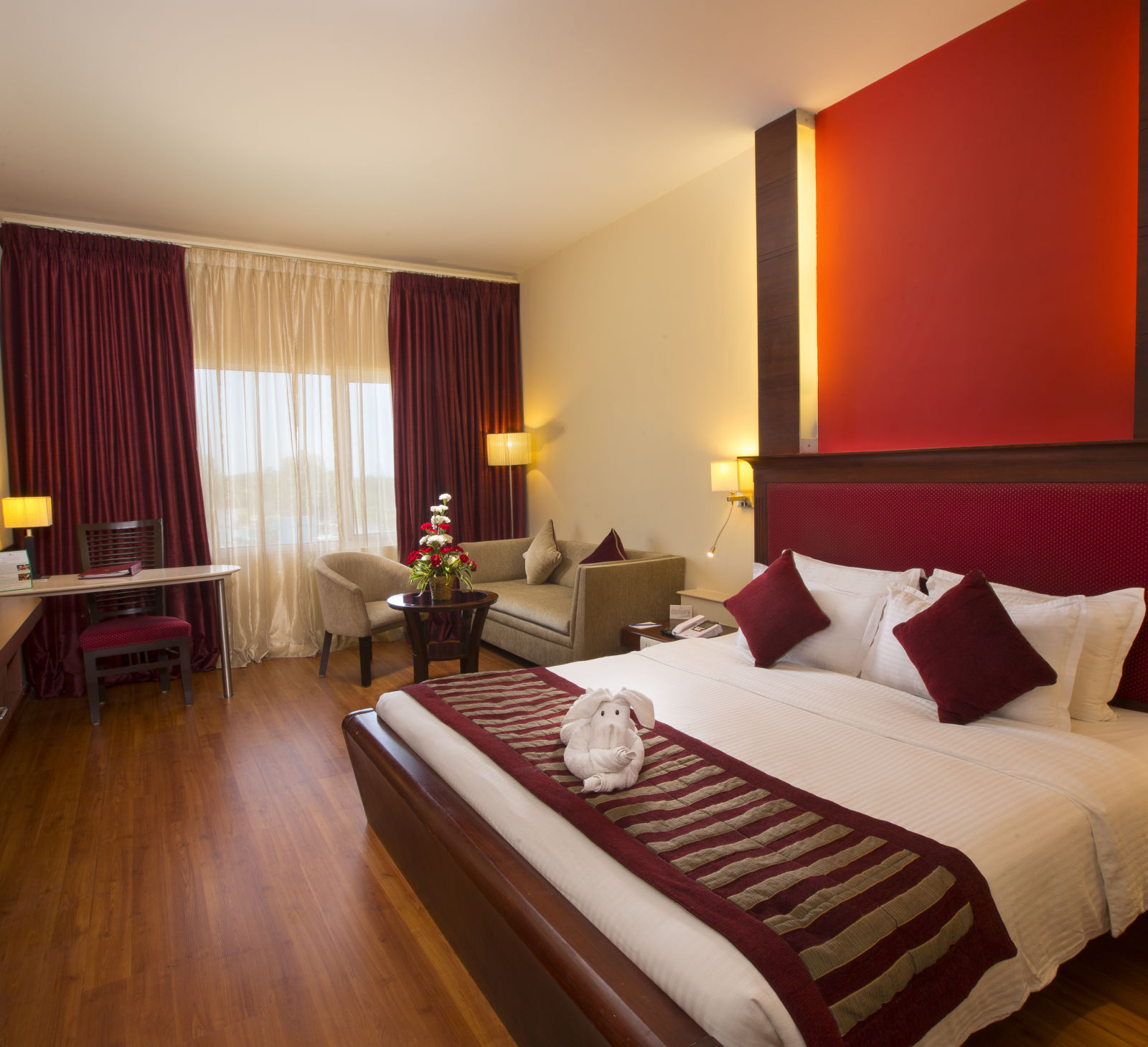 A well-appointed room with a comfortable bed, seating areas, a TV, and lamps.