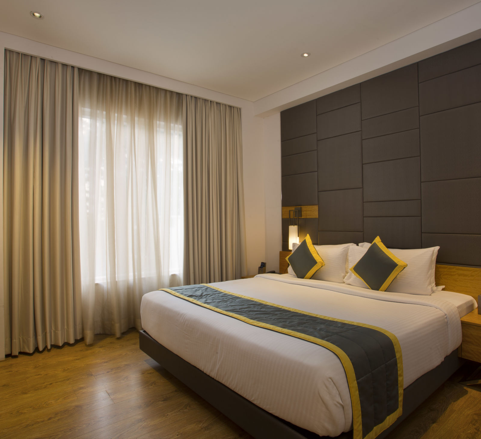 view of a bedroom with a large bed facing a television and two side drawers, one on each side of the bed - Hotel Fountain Tree By TGI - JP Nagar, Bangalore