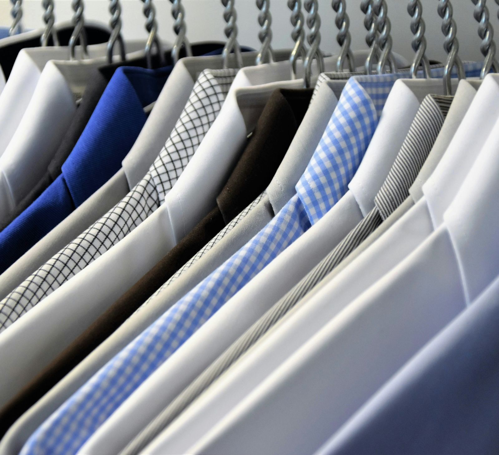 A close-up of a rack of shirts in various shades of blue and patterns, displayed in a closet