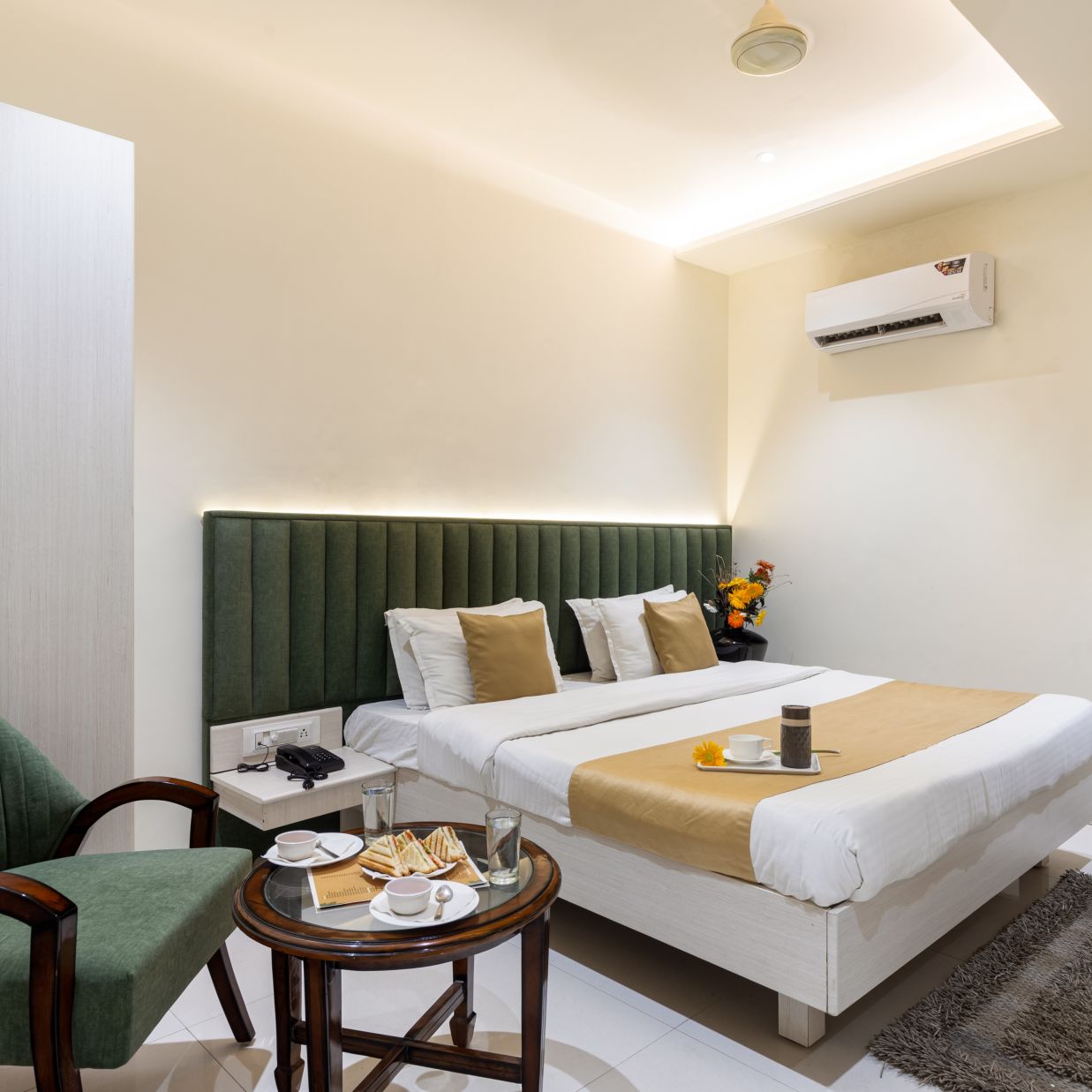 A sofa and a double bed at Deluxe Room at Meghdoot Hotel